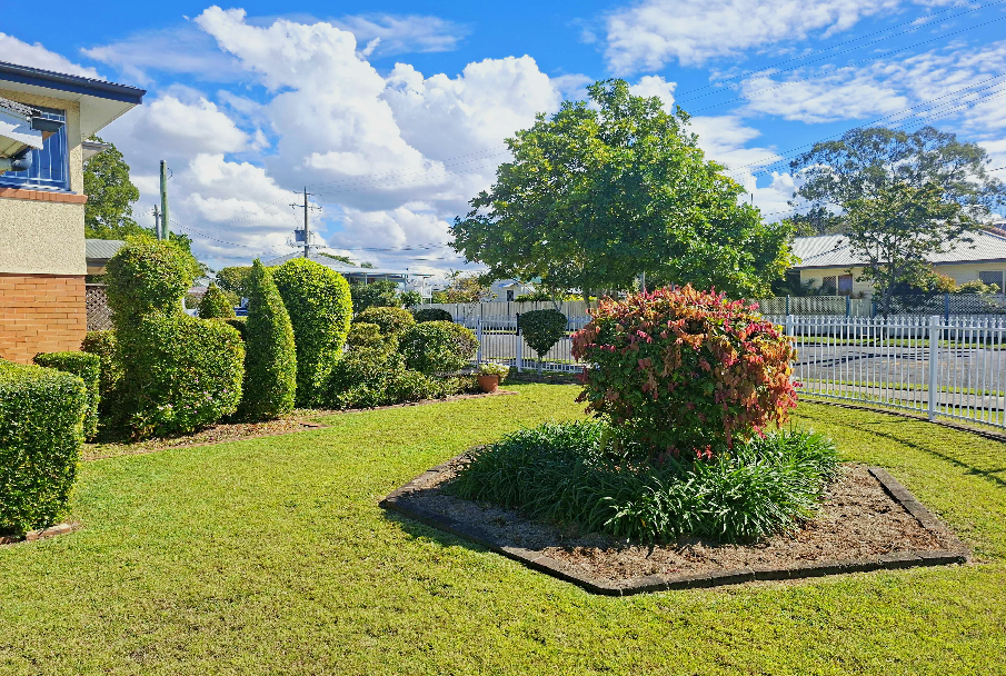 Neatly maintained garden bed with shrubs and freshly mown lawn after an NDIS gardening visit